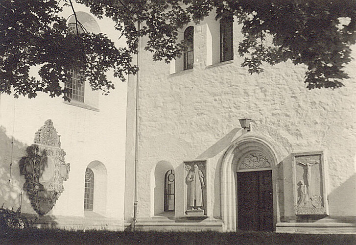Eine Eingangstür zur Klosterkirche Marienwerder im nördlichen Teil, daneben sind Reliefs aus Stein an der Wand angebracht.