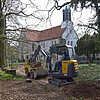 Zwei Baumaschinen arbeiten an einer Fläche, die zum Friedhof gehört, vor der Kirche Marienwerder.