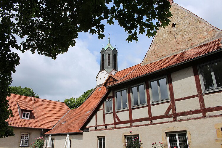 Es sind Gebäudeteile des Klosters Marienwerder in Fachwerk von Innenhof betrachtet zu sehen, im Hintergrund ragt der Kirchturm hervor.