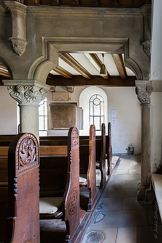 Auf der Detailaufnahme sind Verzierungen an den hölzernen Kirchenbänken und den Säulen zu sehen.