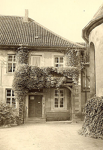 Eingangsbereich des Klosters Marienwerder Mitte des 20. Jahrhunderts mit Flügeltür und einem Balkon, der mit Pflanzen bewachsen ist.